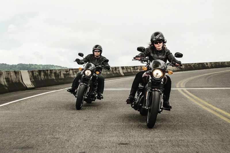 a woman and a man riding down the highway on a Harley-Davidson Street 500/750