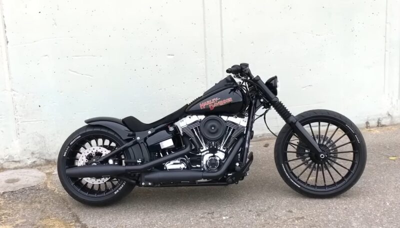 A black custom Harley-Davidson motorcycle parked against a white wall
