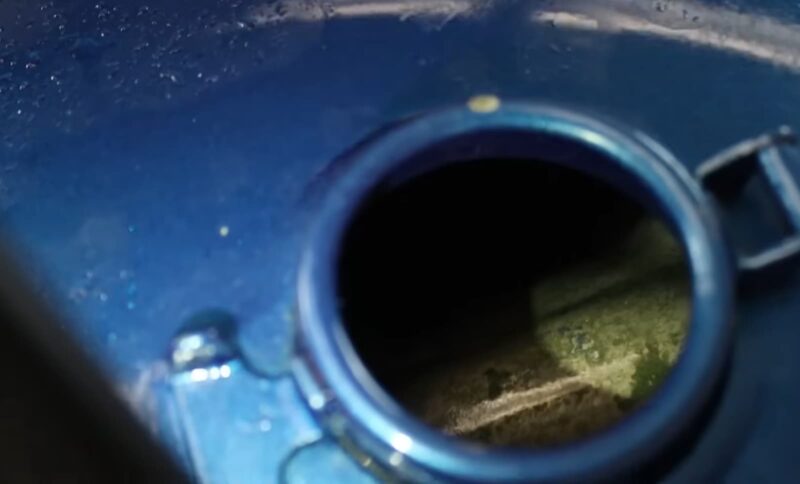 A close-up of a motorcycle's gas tank opening showing signs of rust